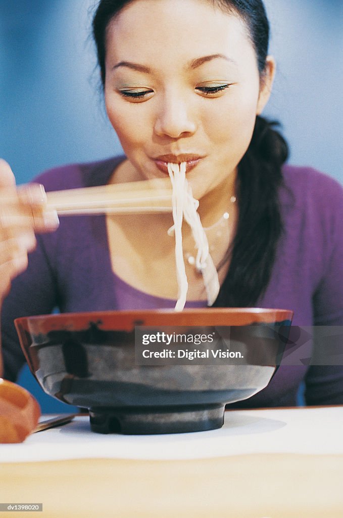 Young Woman Eating Noodles From a Bowl Using Chopsticks