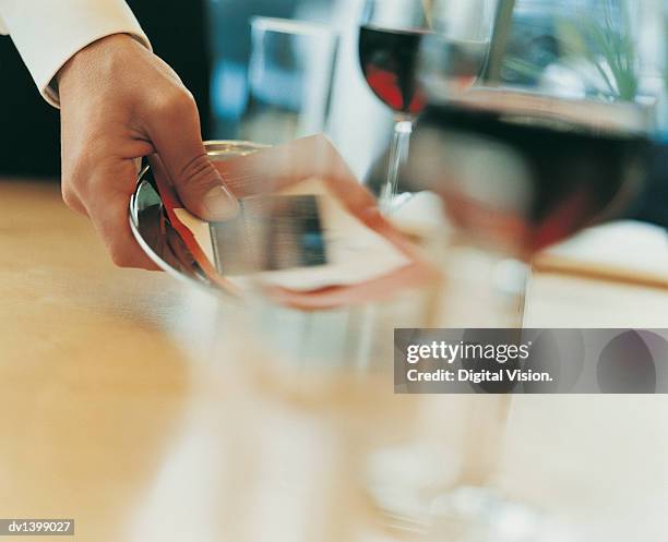 waiter placing a bill and a bank card on a table in a restaurant - card table stock pictures, royalty-free photos & images