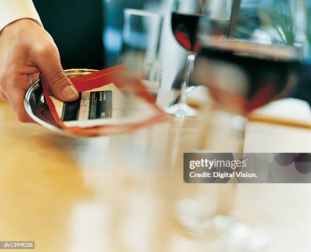 waiter placing a bill and a bank card on a table in a restaurant - card table stock pictures, royalty-free photos & images