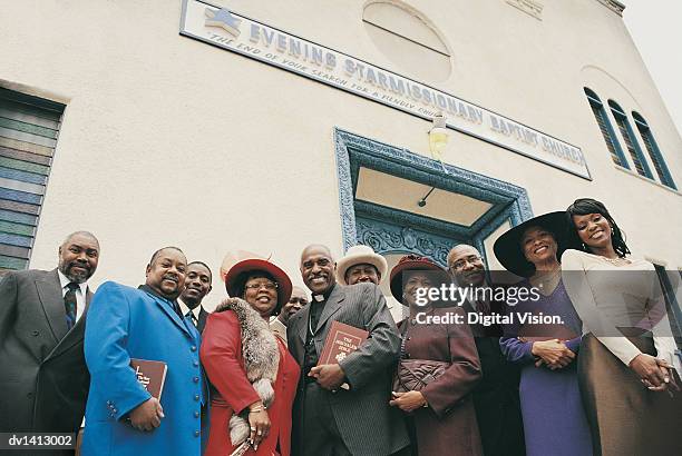 portrait of a line of people standing outside a church with a vicar - geestelijken stockfoto's en -beelden