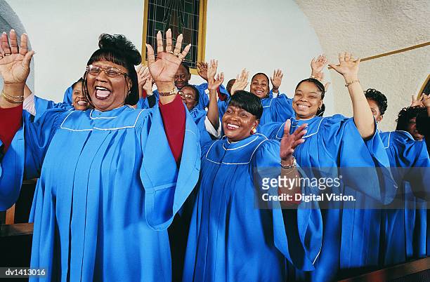 twelve gospel singers with raised hands singing in a church service - religious service stock-fotos und bilder