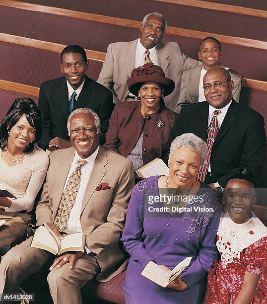 portrait of a three generational family sitting in church pews holding bibles - black people in church stock pictures, royalty-free photos & images