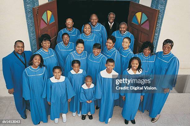 portrait of a priest standing with a choir of gospel singers at the entrance of a church - religieuze muziek stockfoto's en -beelden