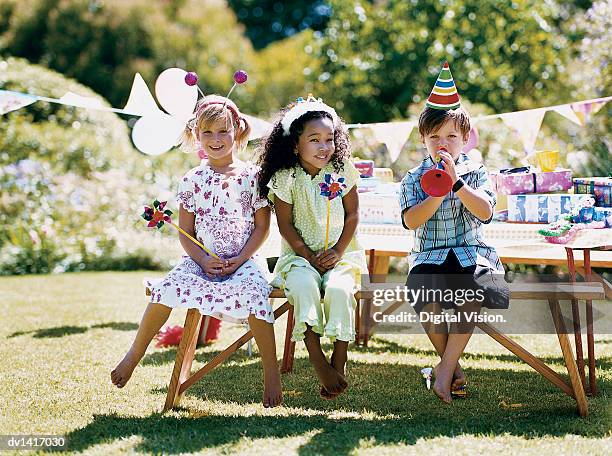 two girls and one boy sitting at a garden table at a birthday party - deely bopper stock pictures, royalty-free photos & images