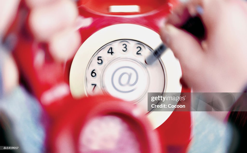 Human Hand Dialling Internet Connection on a Red Rotary Phone