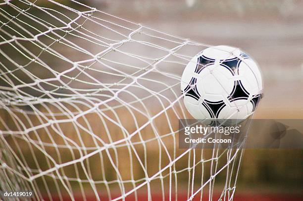 football trapped in a goal net, close-up - pallone da calcio foto e immagini stock