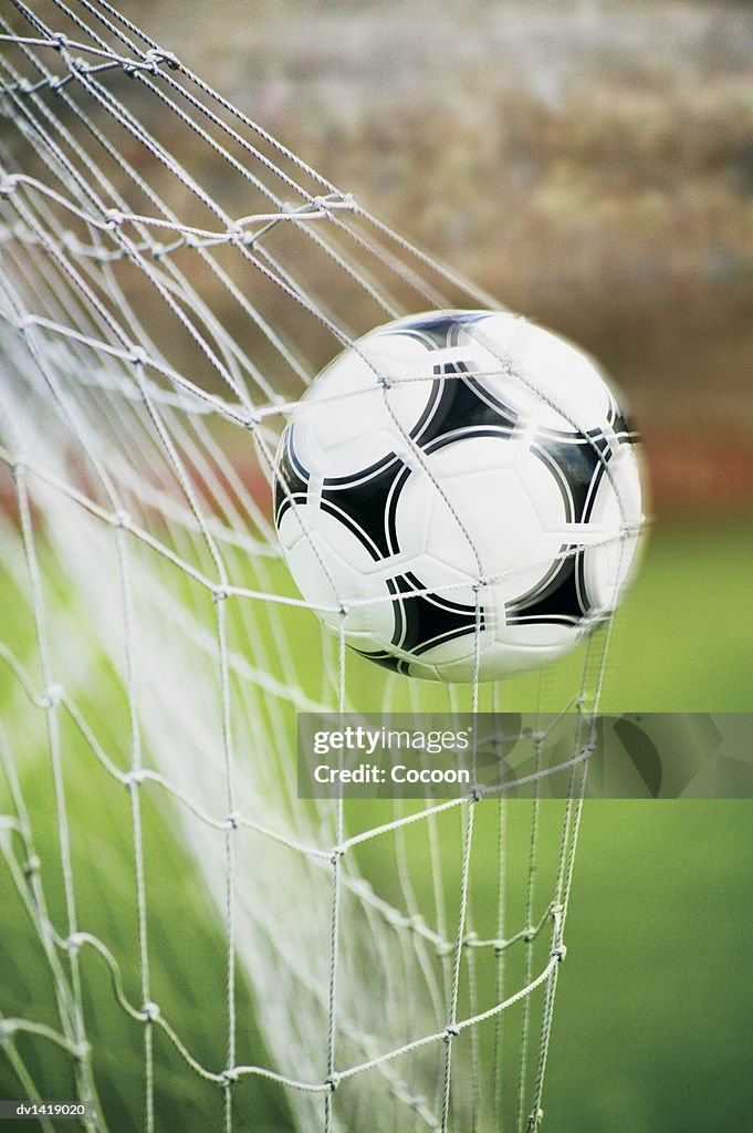 Close-Up of a Football Trapped in a Goal Net on a Football Pitch