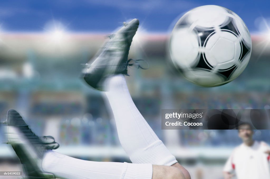 Footballers Legs Upside Down and Kicking the Ball