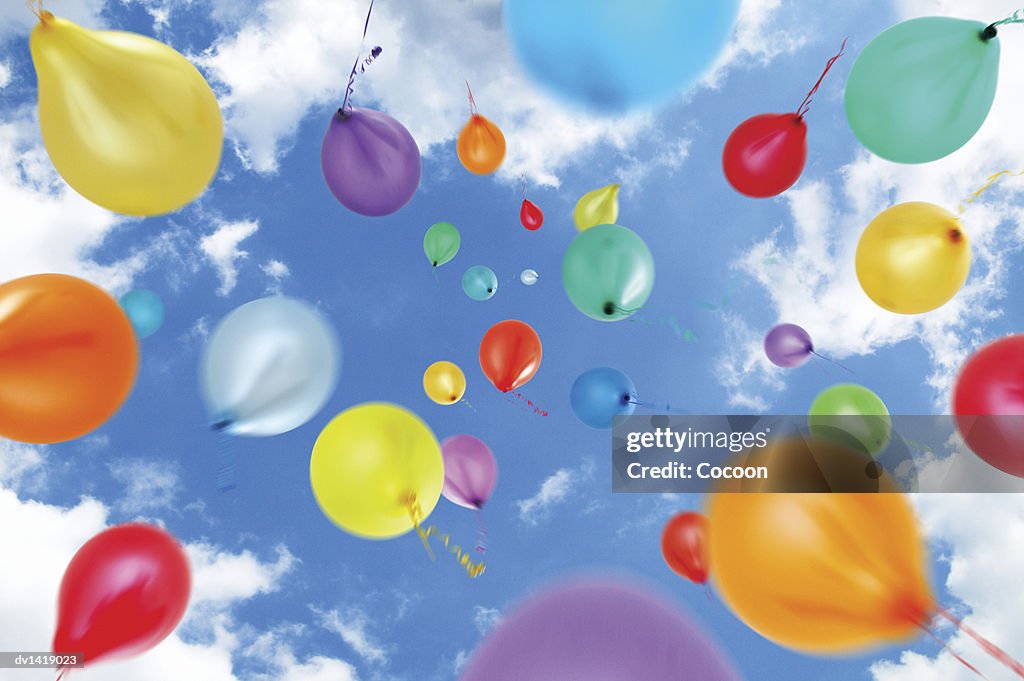 Multi-Coloured Balloons Move Upwards Into a Summer Sky