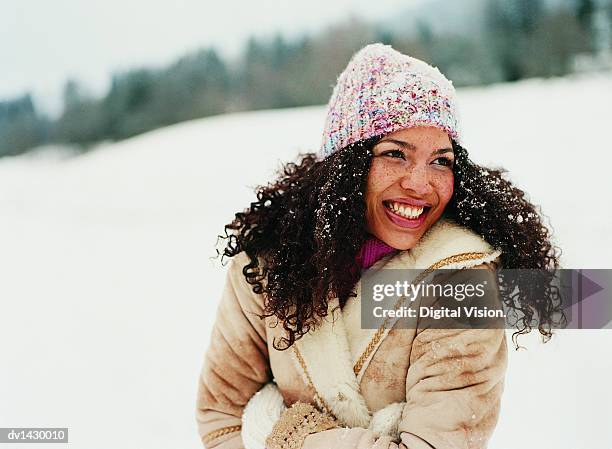 portrait of a young woman wearing a hat in the snow - winter coats stock-fotos und bilder