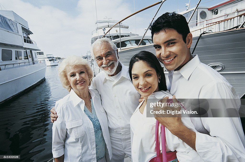 Four Smiling Adults Standing in a Marina With Moored Motorboats in the Background