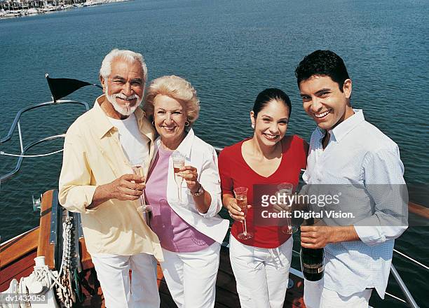 four smiling adults standing on the deck of a boat with champagne - wine bottle transport stock pictures, royalty-free photos & images