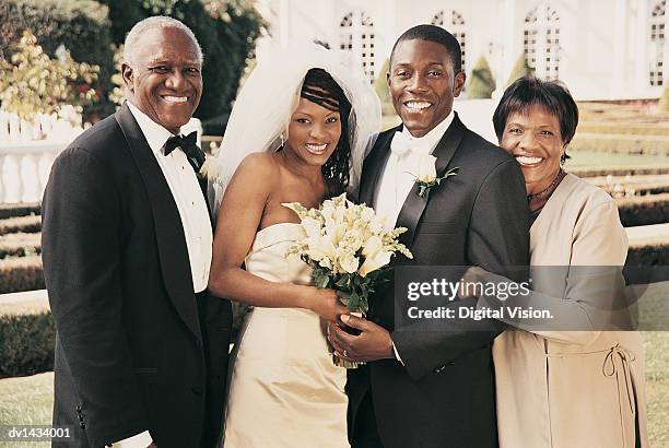 bride and groom stand side-by-side with parents in the grounds of a wedding reception - mother and daughter smoking stock-fotos und bilder