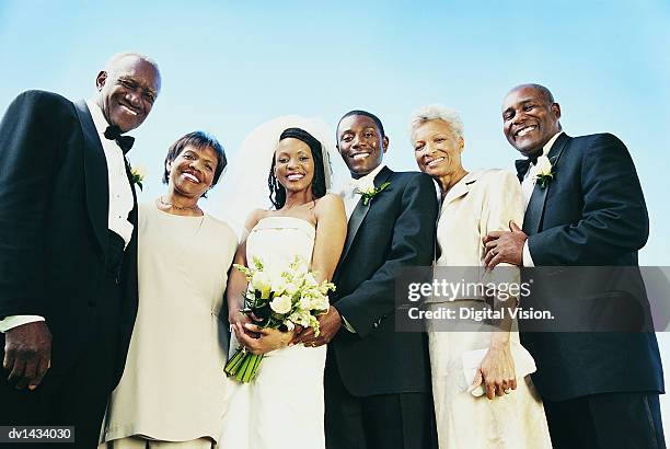 bride and groom stand with parents for a wedding portrait - mother and daughter smoking stock-fotos und bilder