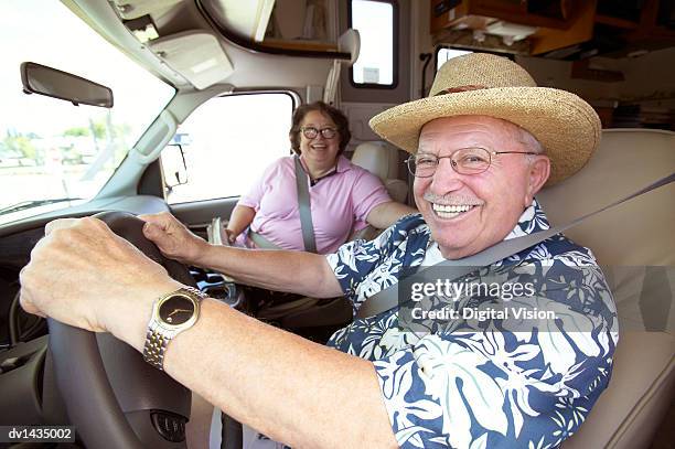 senior couple sit in the front seat of a motor home, the man sitting at the steering wheel, laughing - chapeau de soleil photos et images de collection