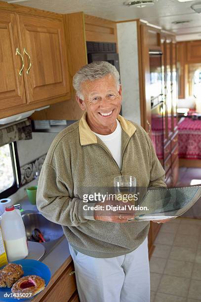 senior man has breakfast by the kitchen counter of a motor home, planning his journey with a map - the journey stock pictures, royalty-free photos & images
