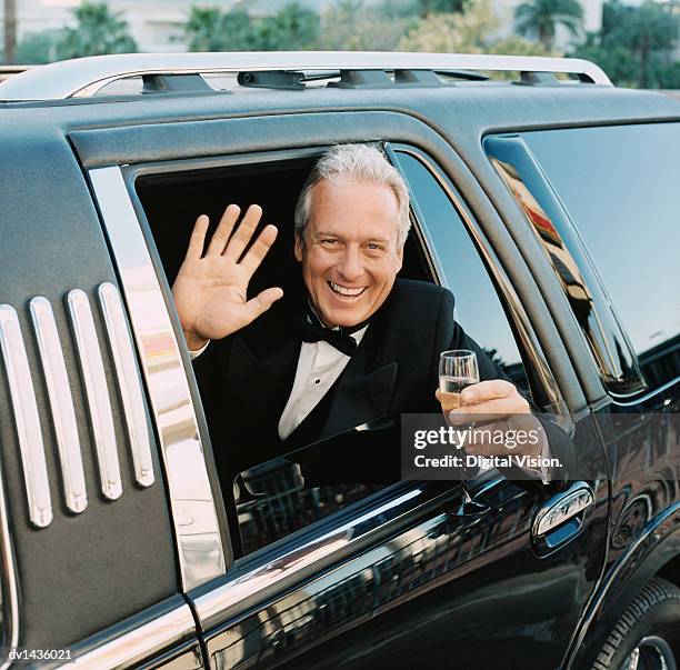 mature man sitting in a limousine waving out of the window holding a glass of champagne - statussymbol bildbanksfoton och bilder