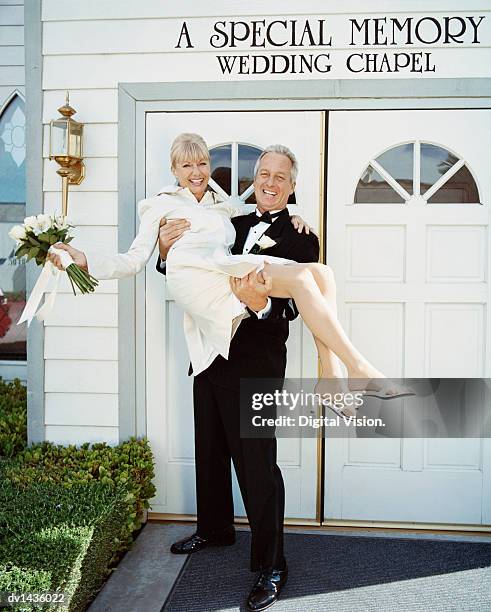 mature newlywed couple outside a wedding chapel in las vegas. groom carrying the bride. - las vegas wedding stock pictures, royalty-free photos & images