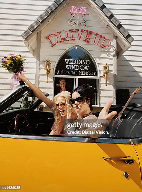 newlywed couple sitting in a yellow convertible in front of a wedding chapel - vegas wedding stock pictures, royalty-free photos & images