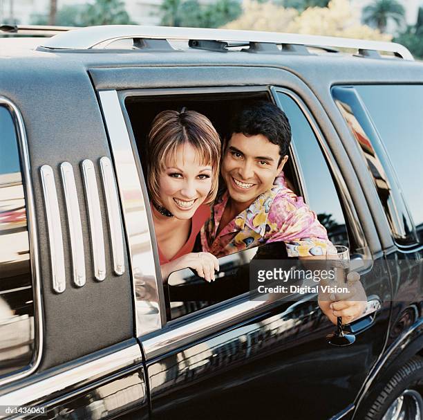 happy couple looking out of a limousine window, man holding a champagne glass - símbolo de status imagens e fotografias de stock
