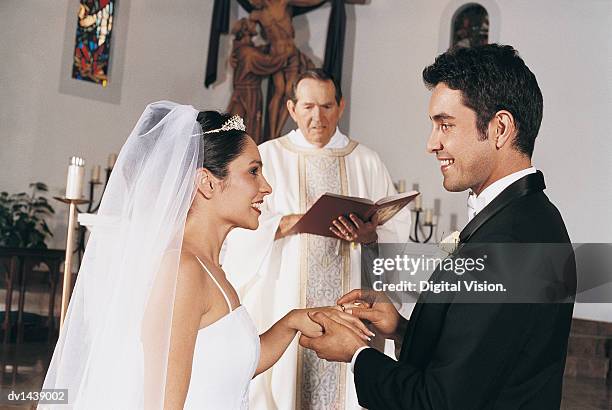 bride and groom exchange rings in church ceremony - man and woman holding hands profile stockfoto's en -beelden