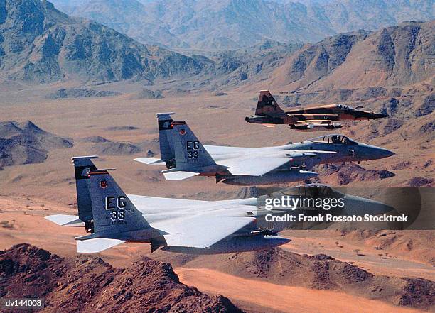 squadron of military airplanes over desert mountains - formationsfliegen stock-fotos und bilder