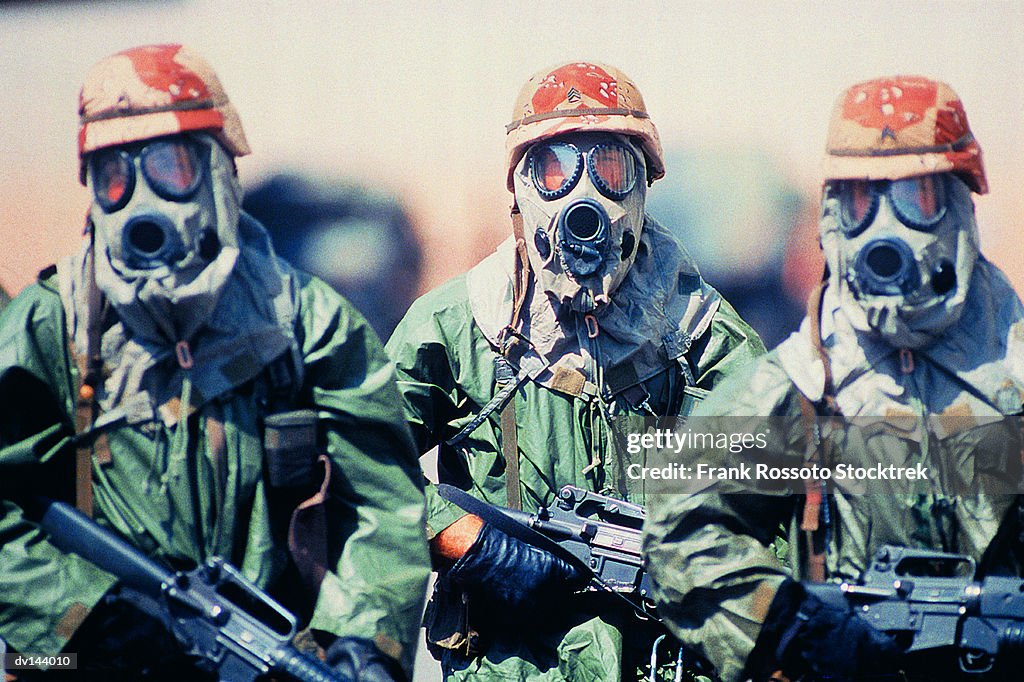 Troop of soldiers in camouflage uniforms, helmets and gas masks