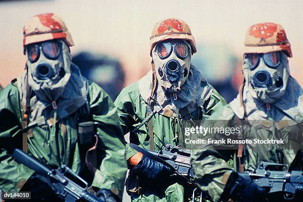 troop of soldiers in camouflage uniforms, helmets and gas masks - biochemical weapon stock pictures, royalty-free photos & images