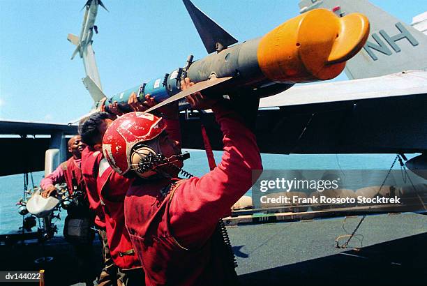 ordinance personnel loading a missile onto a military airplane - marine engineering stockfoto's en -beelden