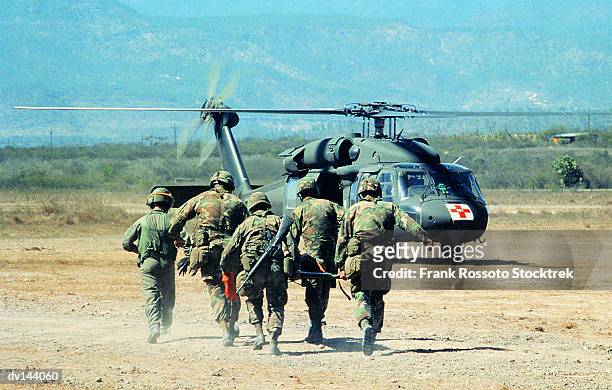 medical evacuation team carrying stretcher towards uh-60 blackhawk helicopter on ground - army soldier photos fotografías e imágenes de stock