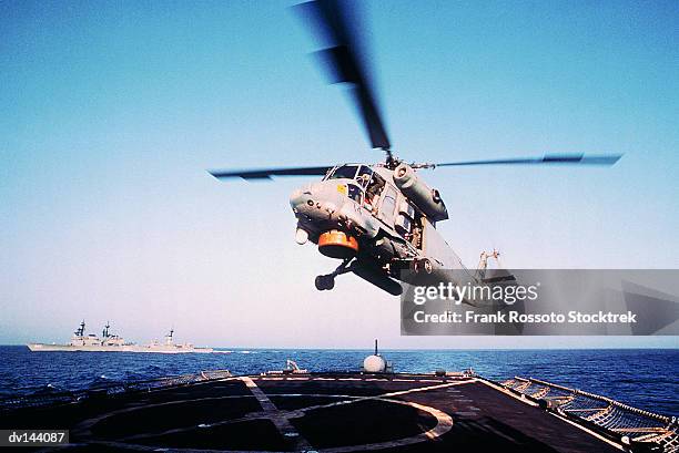 military helicopter landing on deck of aircraft carrier - military helicopter fotografías e imágenes de stock