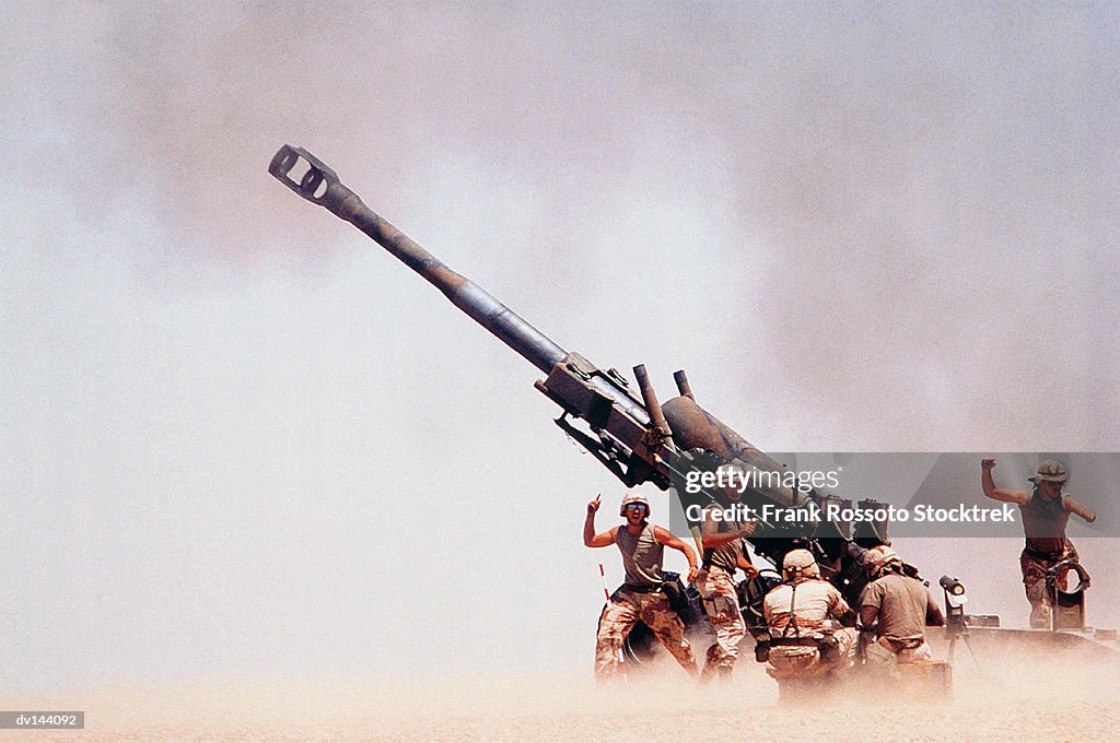 Troops on ground firing M198 Howitzer gun