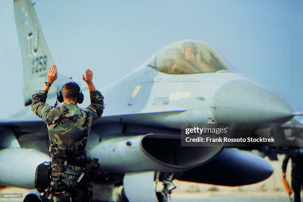 Ground crew signalling to pilot of a Military Airplane