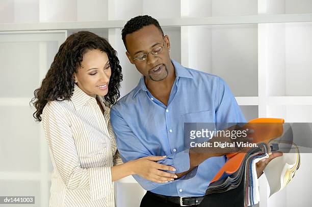 couple stand side by side choosing from a variety of fabric swatches - variety stockfoto's en -beelden