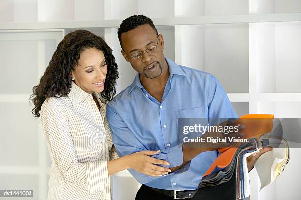 couple stand side by side choosing from a variety of fabric swatches - variety imagens e fotografias de stock