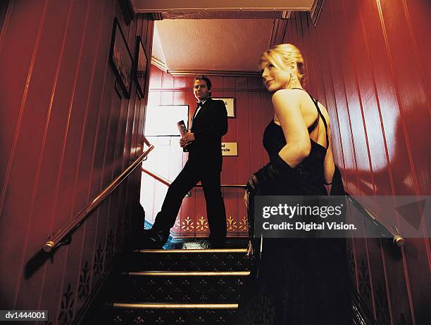 couple in evening wear ascending stairs in a theatre - evening wear stock pictures, royalty-free photos & images