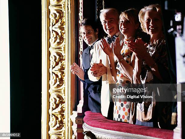 mature and young couples standing in a theatre balcony applauding - ovación de pie fotografías e imágenes de stock