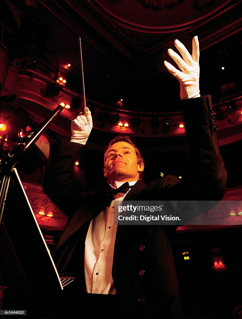 Classical Music Conductor Raising His Arms in an Auditorium