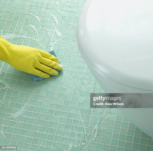 hand in a rubber glove cleaning a tiled floor in a bathroom - clean bathroom stock pictures, royalty-free photos & images