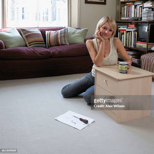 young woman sitting by a chest of drawers in her living room - chest of drawers 個照片及圖片檔