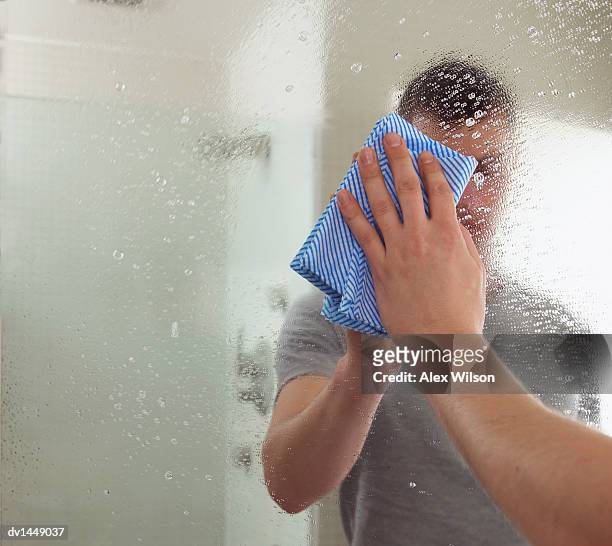 man cleaning a mirror in a bathroom - rubbing stock pictures, royalty-free photos & images