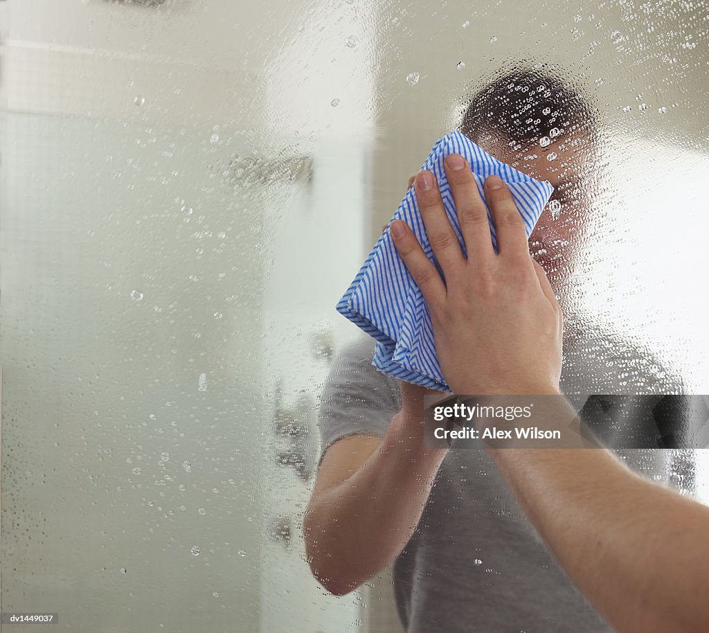 Man Cleaning a Mirror in a Bathroom