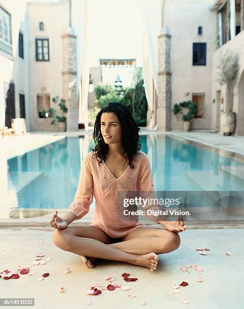 woman sitting poolside in the lotus position with petals around her, marrakesh, morroco - morroco imagens e fotografias de stock