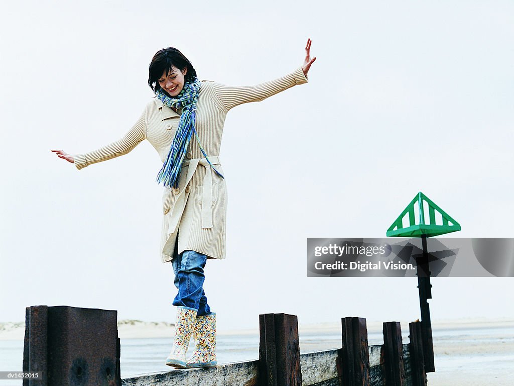 Woman Walks, Balancing With Her Arms Out on a Breakwater