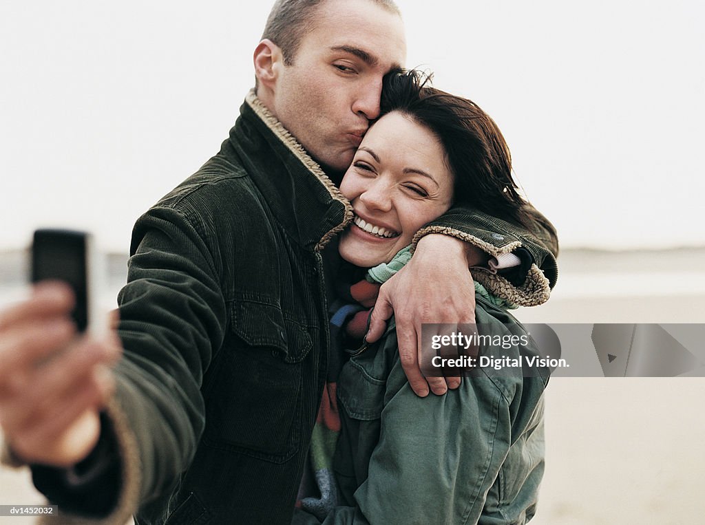 Couple Stand on a Beach Taking a Self-Portrait