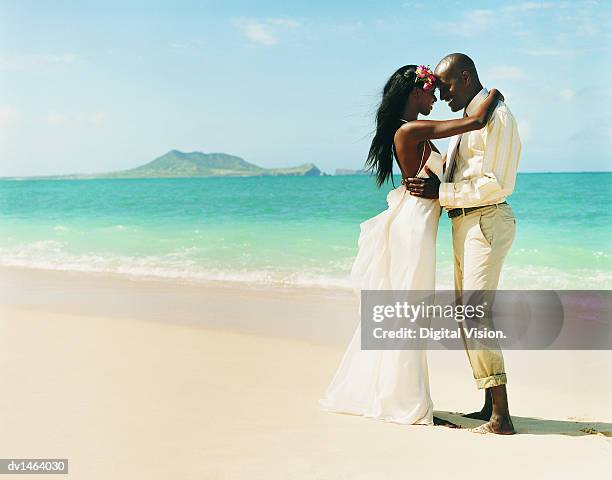 newlywed couple dance face-to-face at the waters edge on a beach - beach wedding fotografías e imágenes de stock