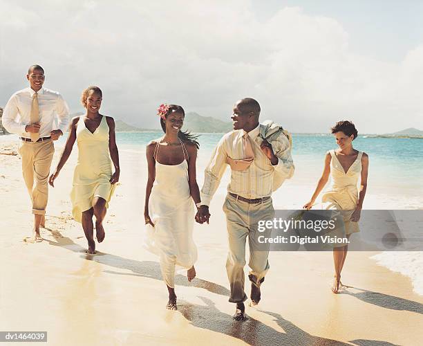 newlywed couple walk at waters edge holding hands accompanied by bridesmaids and best man - black veil brides stock pictures, royalty-free photos & images