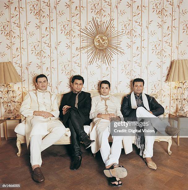 four brothers sitting on an ornate sofa in their living room - ornate house furniture stock-fotos und bilder