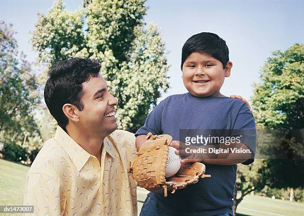 father and son with a basball glove and ball in a park - chubby boy fotografías e imágenes de stock