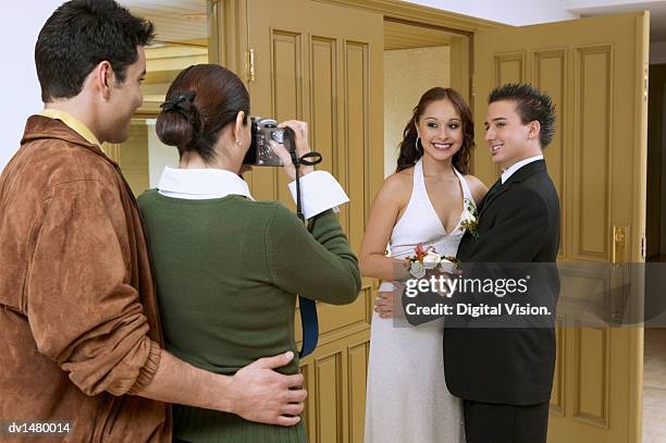 woman with a man taking a picture of a couple at a high school prom - adac stock pictures, royalty-free photos & images